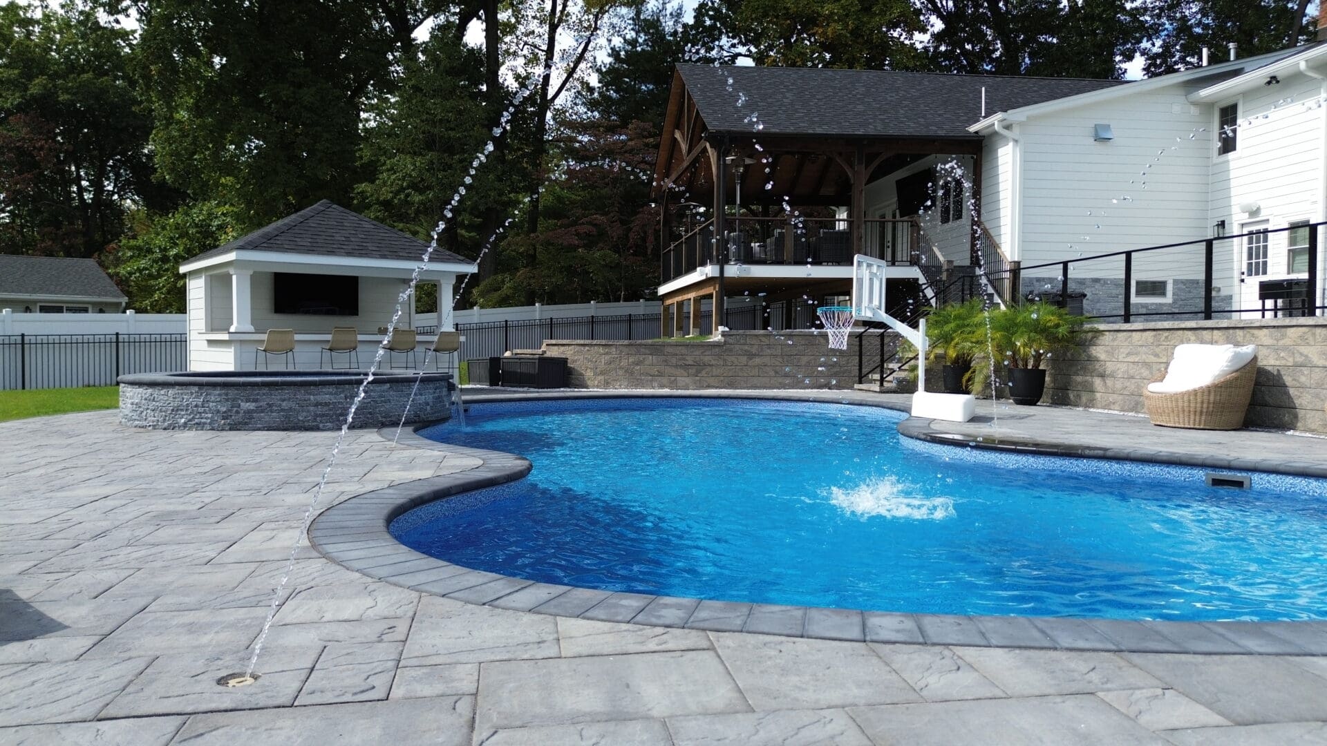 A pool with water jets and a house in the background.