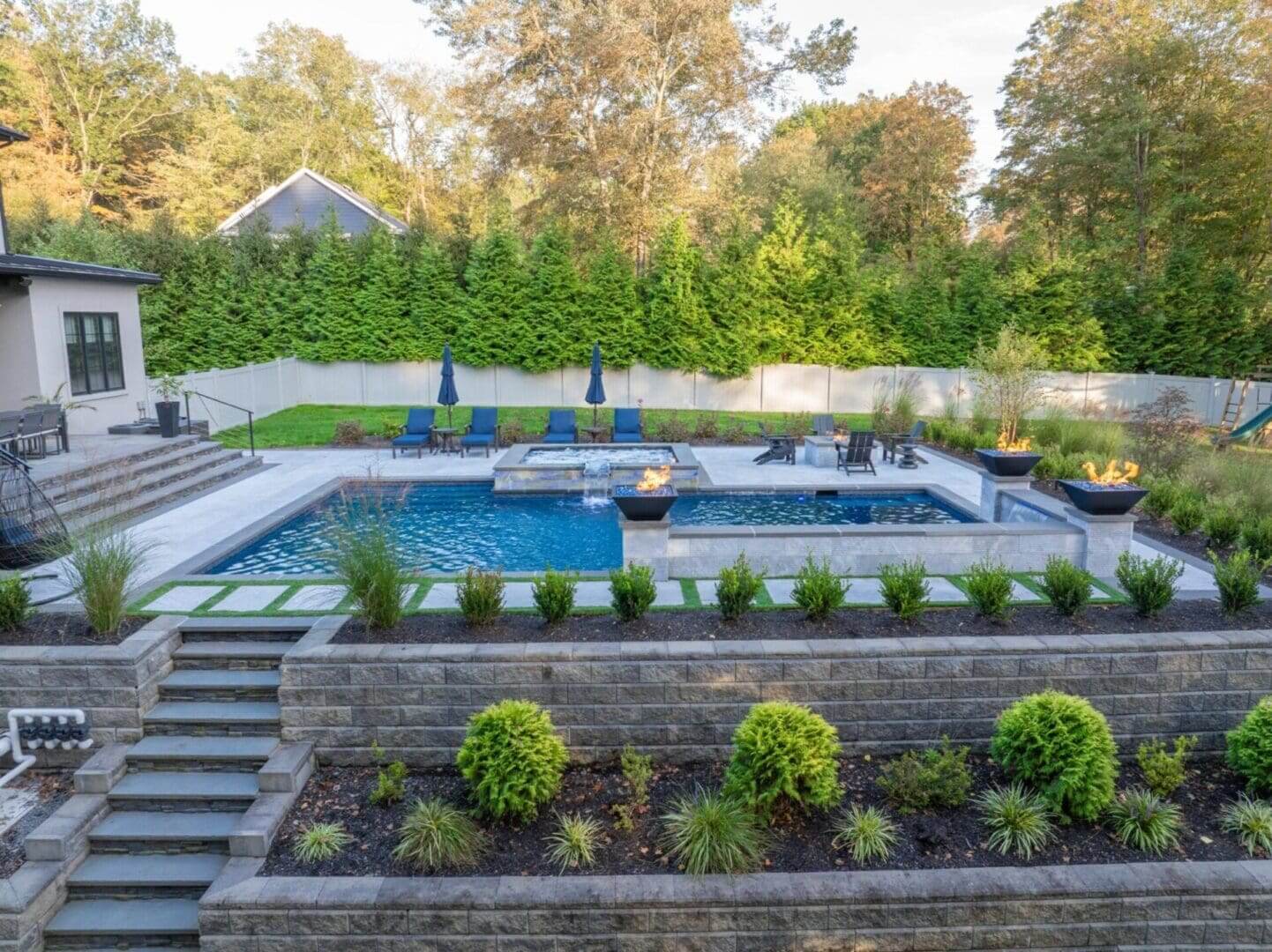Modern terraced backyard pool with fire bowls