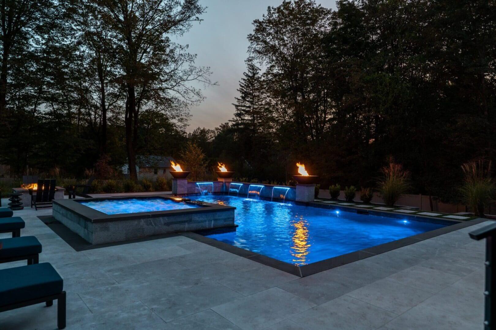 Blue-lit luxury pool with fire bowls