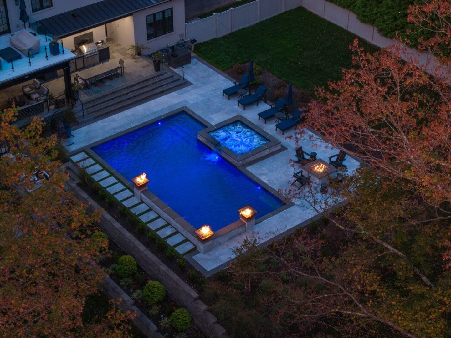 Aerial view of illuminated backyard pool and spa